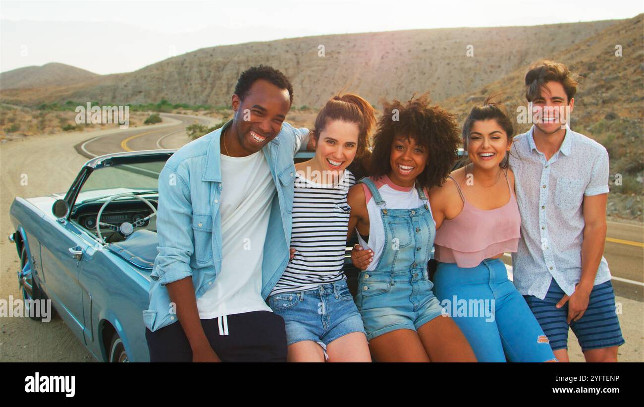 Portrait Of Group Of Friends Sitting In Trunk Of Open Top Car On Road ...