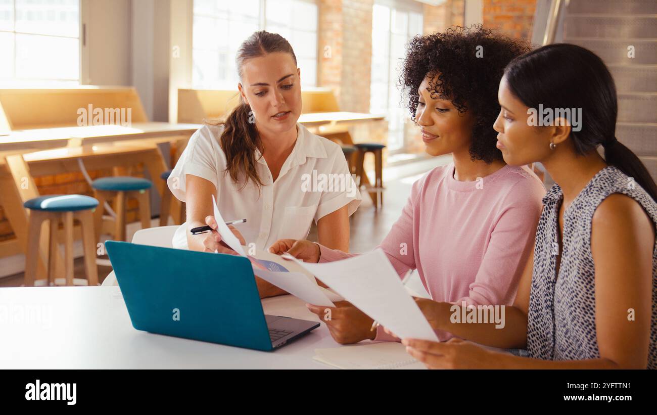 Three Young Businesswomen Meeting In Modern Office Sitting Around Table ...