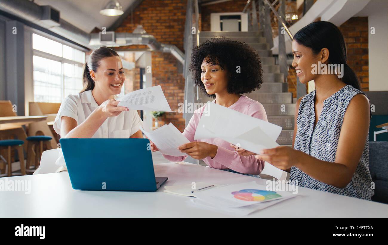 Three Young Businesswomen Meeting In Modern Office Sitting Around Table ...
