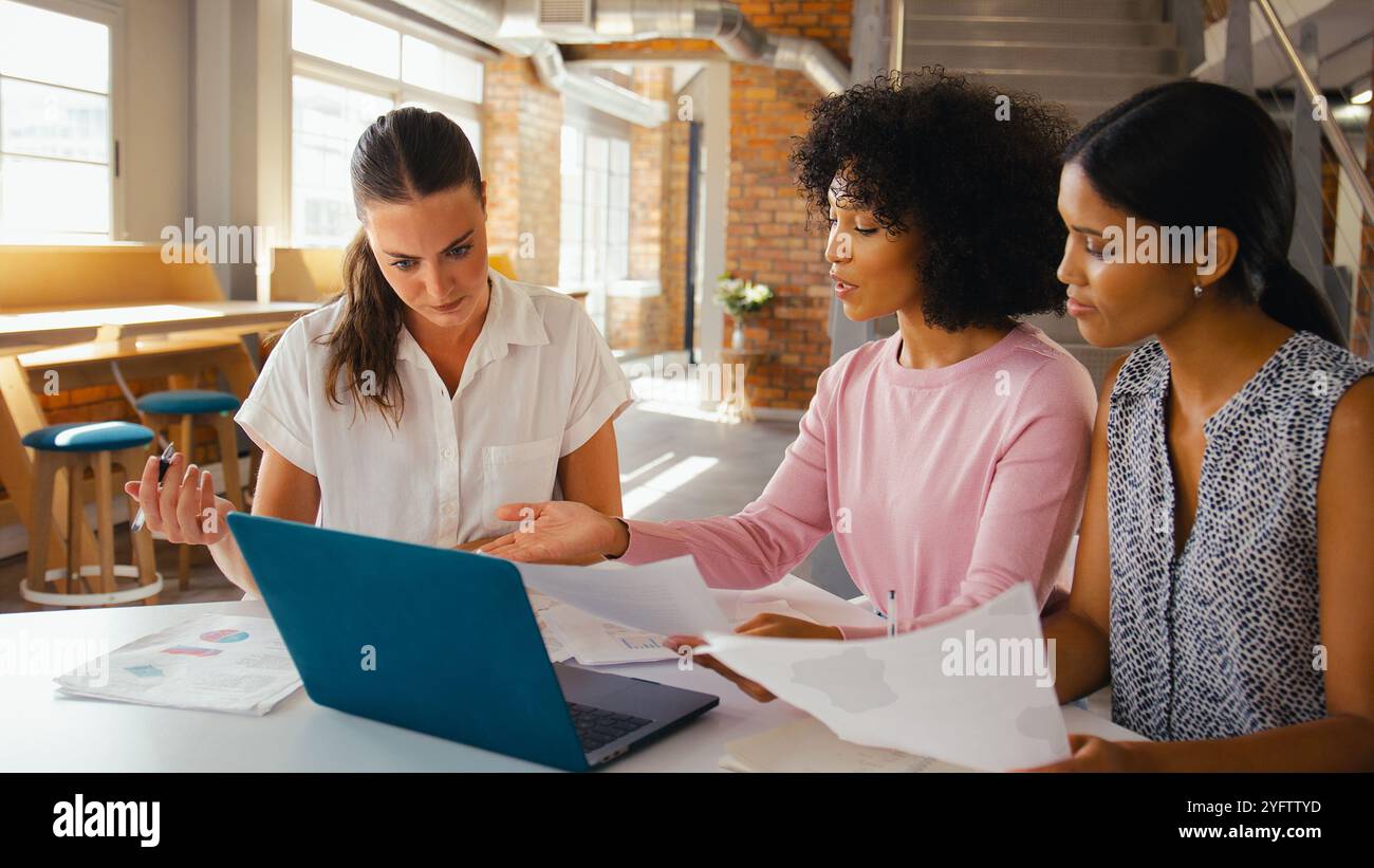 Three Young Businesswomen Meeting In Modern Office Sitting Around Table ...