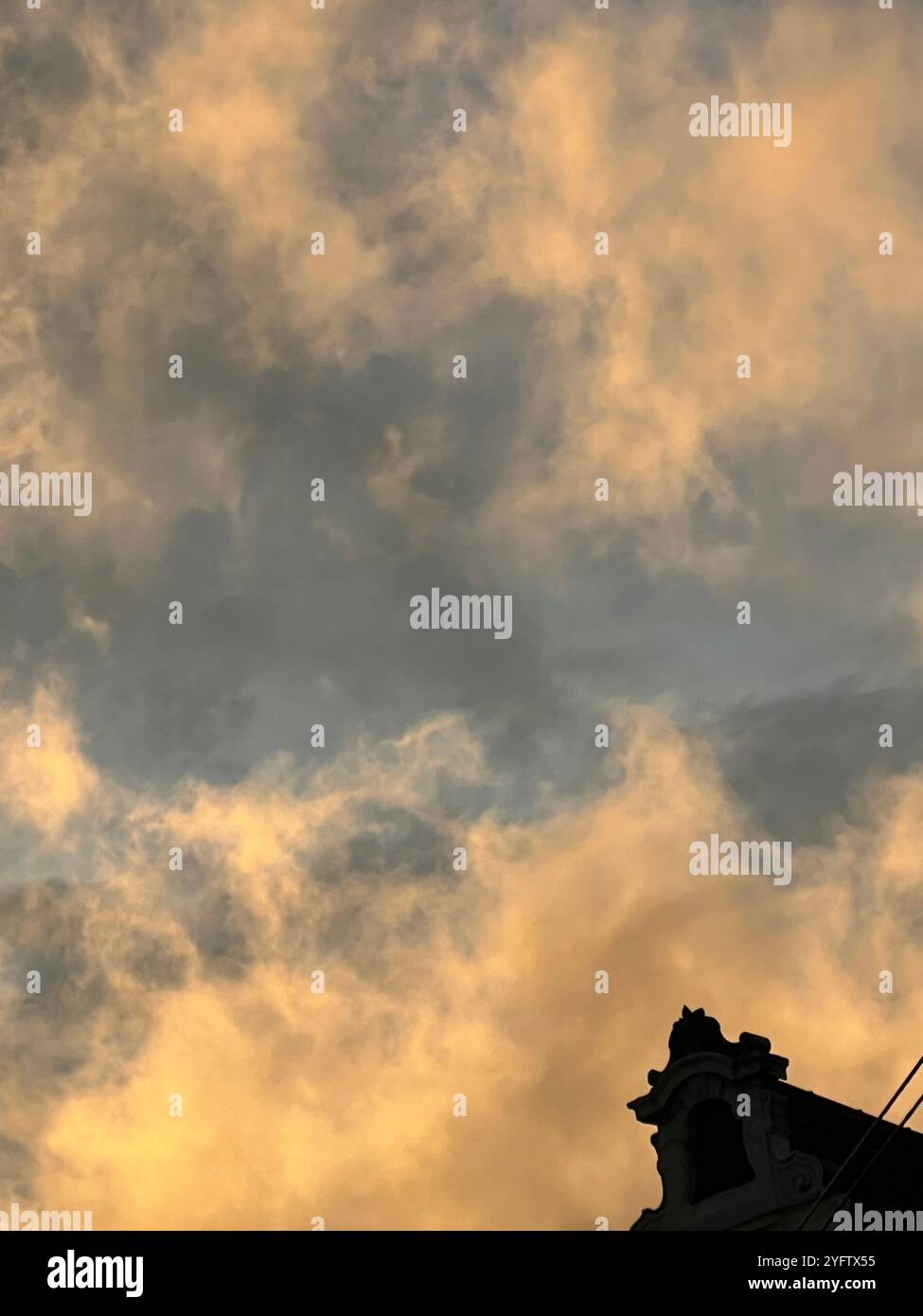 A golden sunset sky filled with textured clouds contrasts with the dark silhouette of a historical building Vienna, Austria - Smartphone Captured Stock Image A golden sunset sky filled with textured clouds contrasts with the dark silhouette of a historical building Vienna, Austria - Smartphone Captured Stock Image