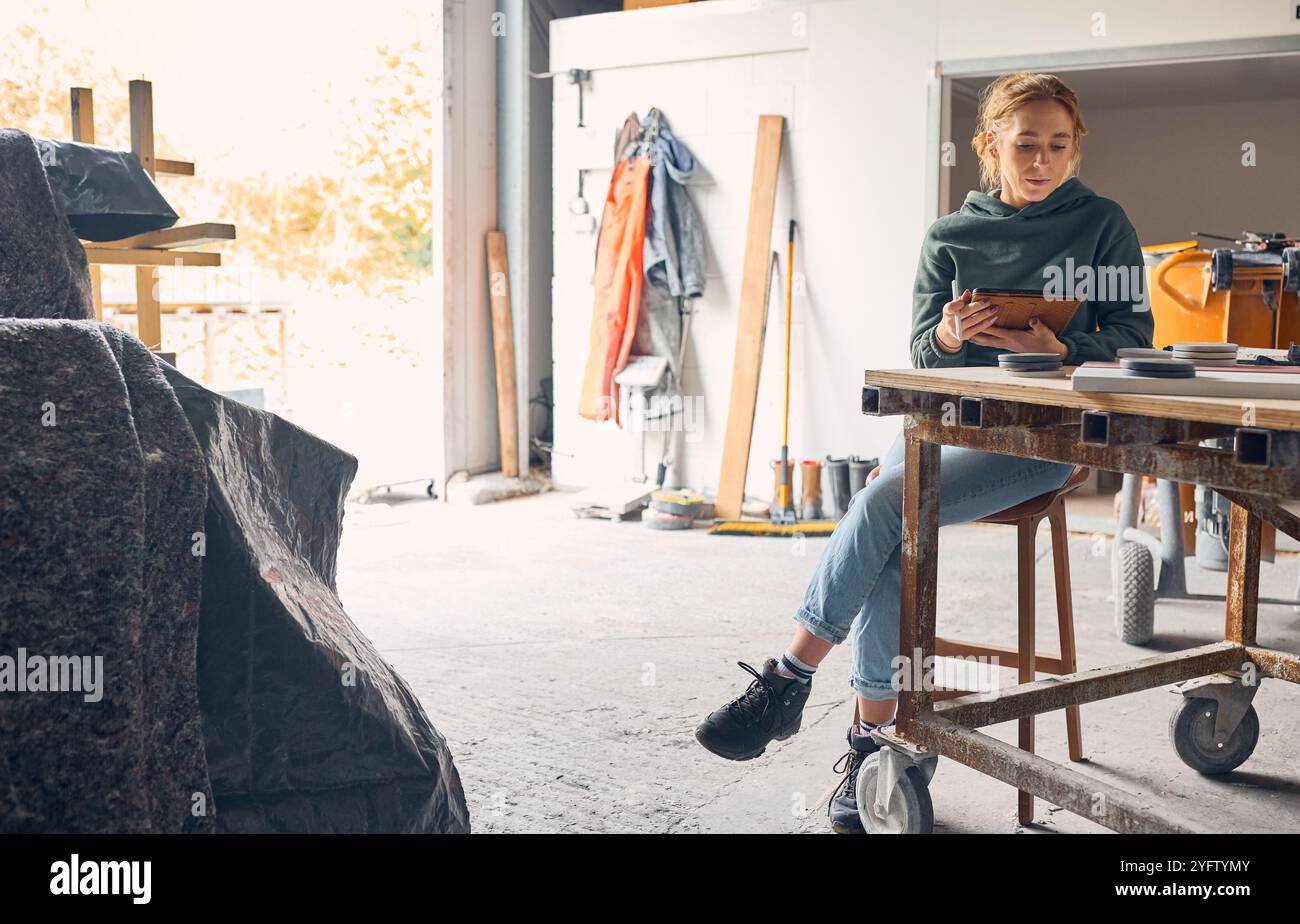 Female Worker In Concrete Workshop Using Digital Tablet And Stylus Stock Photo