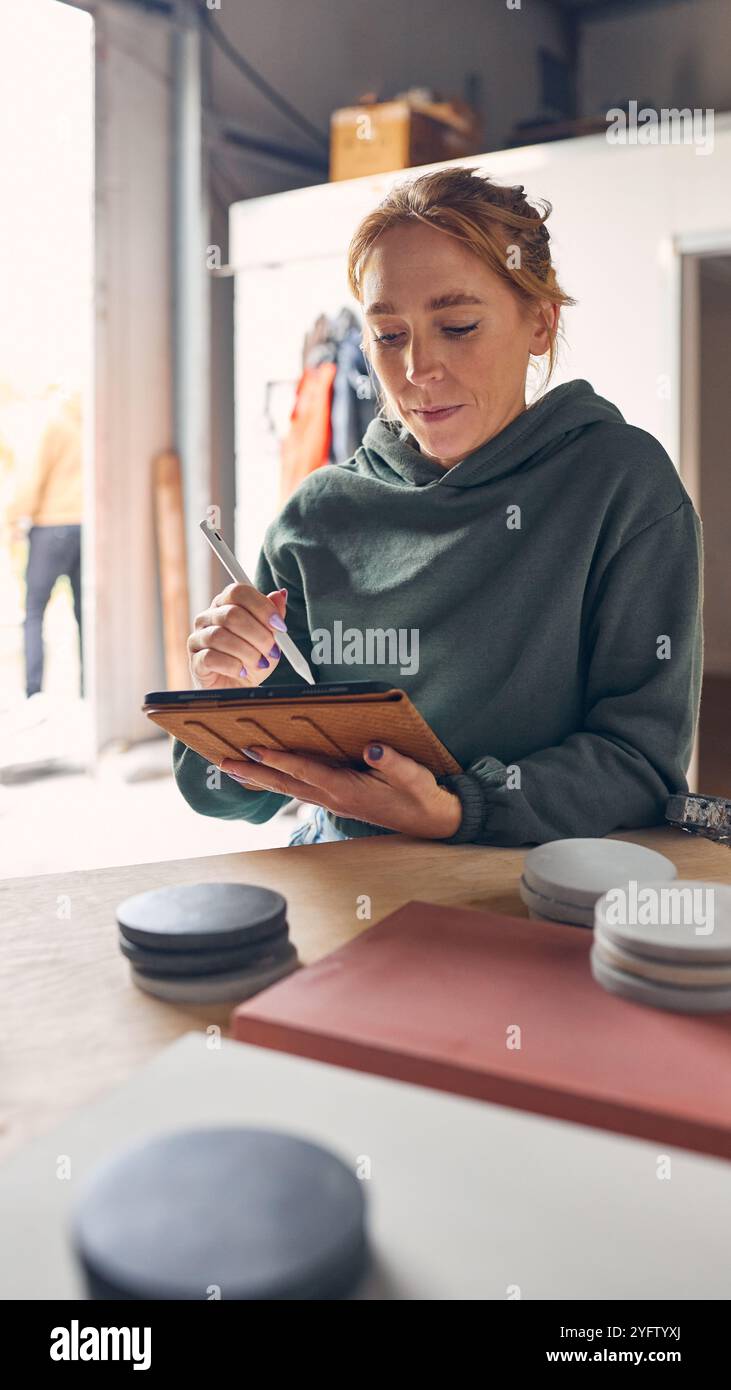 Female Worker In Concrete Workshop Using Digital Tablet And Stylus Checking Samples Stock Photo