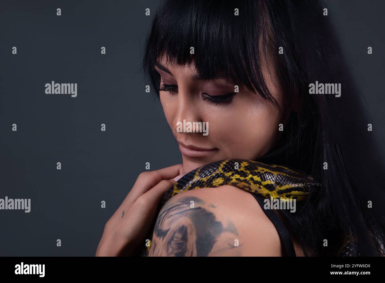 Image of the girl with yellow anaconda on shoulders in shadows Stock Photo