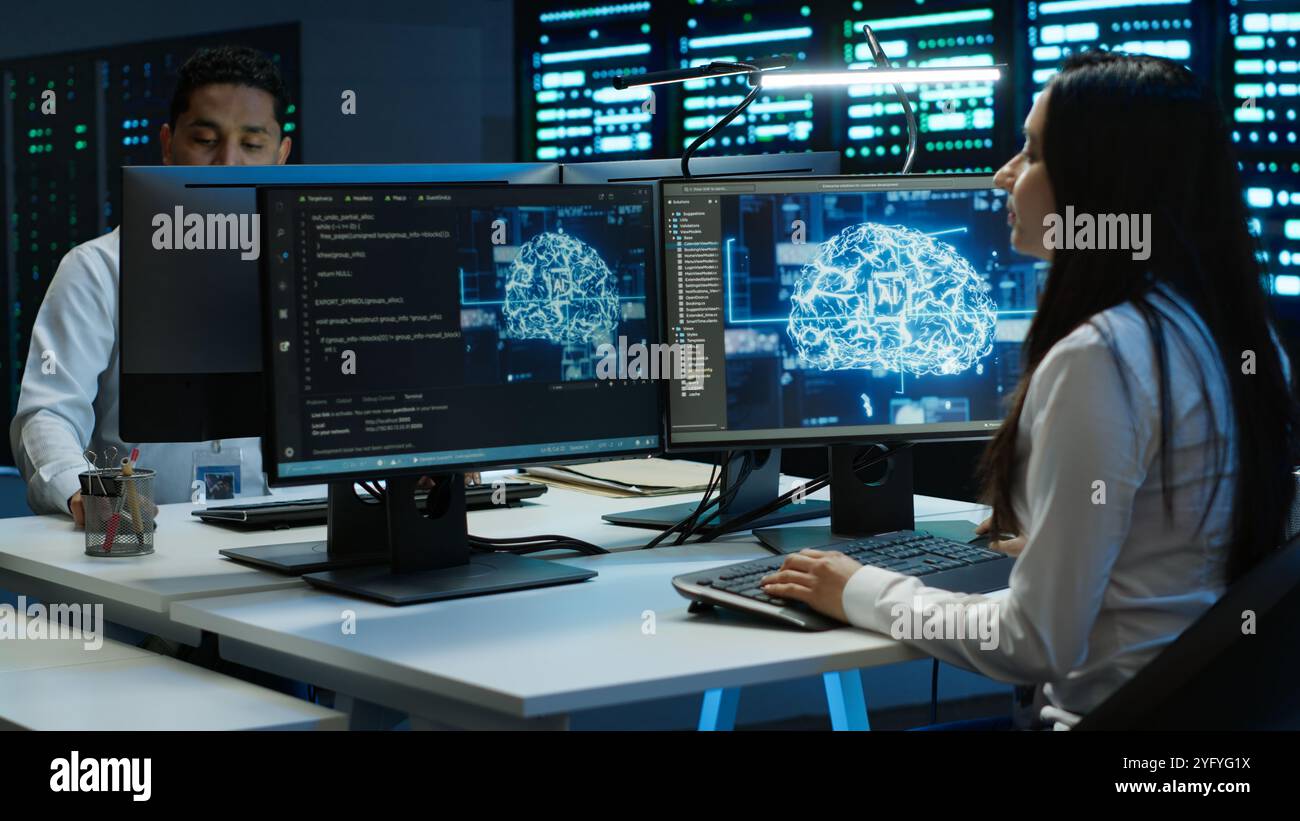 Team of engineers using AI tech on computer to do checkup in server room. Data center workers using artificial intelligence technology to process datasets for training, camera A Stock Photo