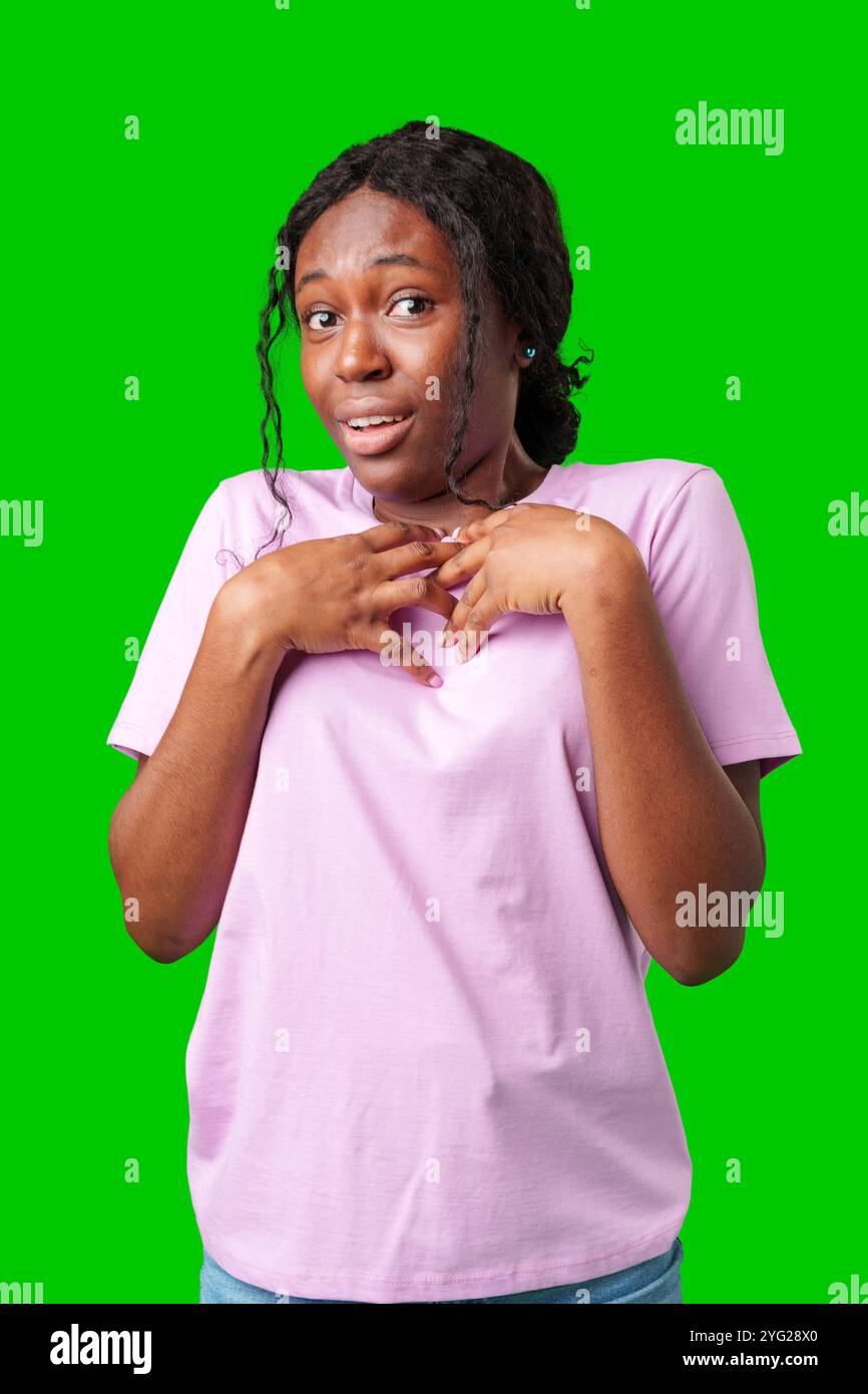 Surprised young woman against a vibrant green background expressing astonishment or shock Stock Photo