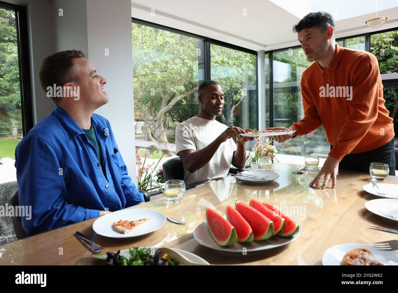 Friends enjoying pizza at table Stock Photo