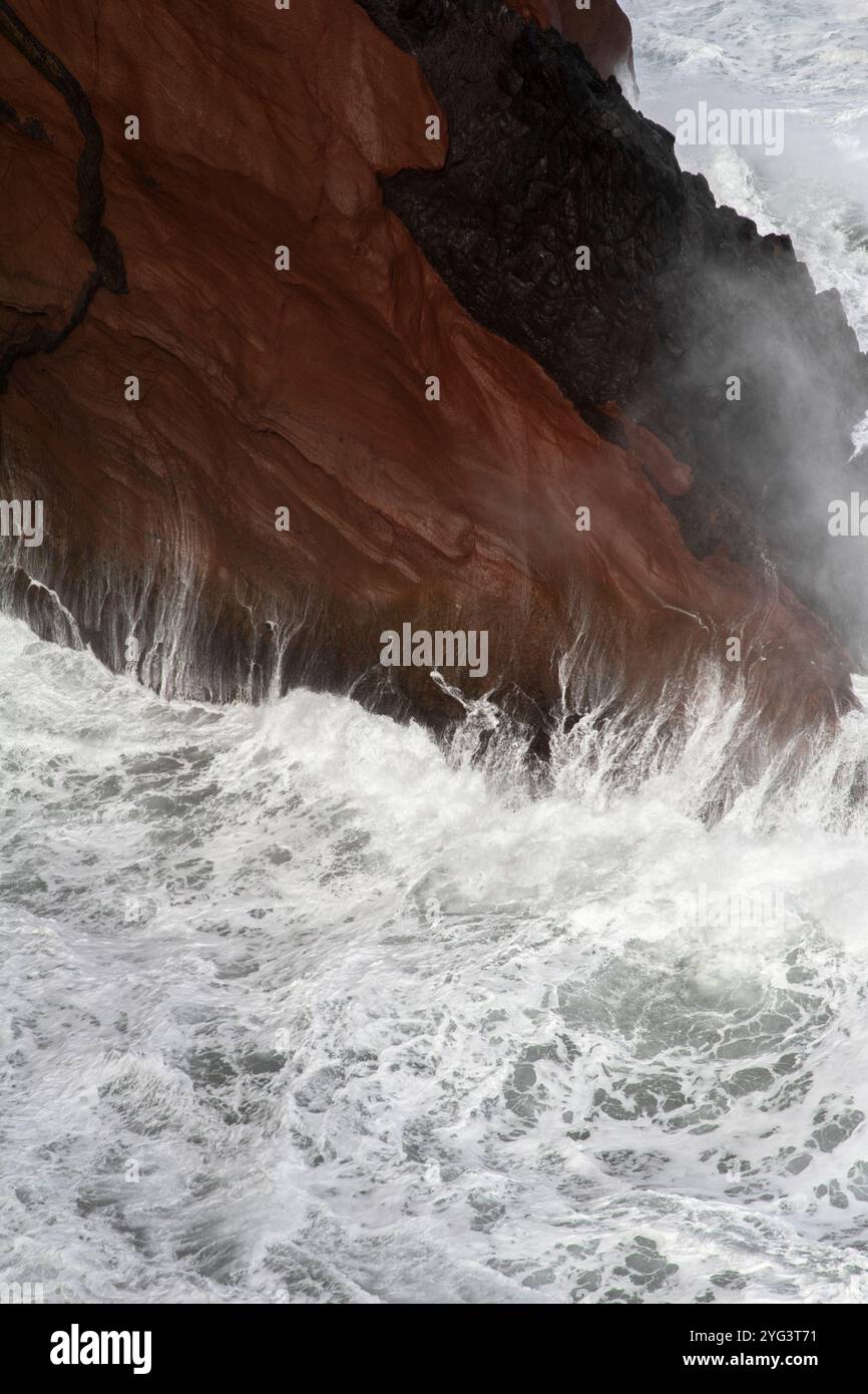 Sea waves that hit red rocks and create beautiful splashes and shapes ...