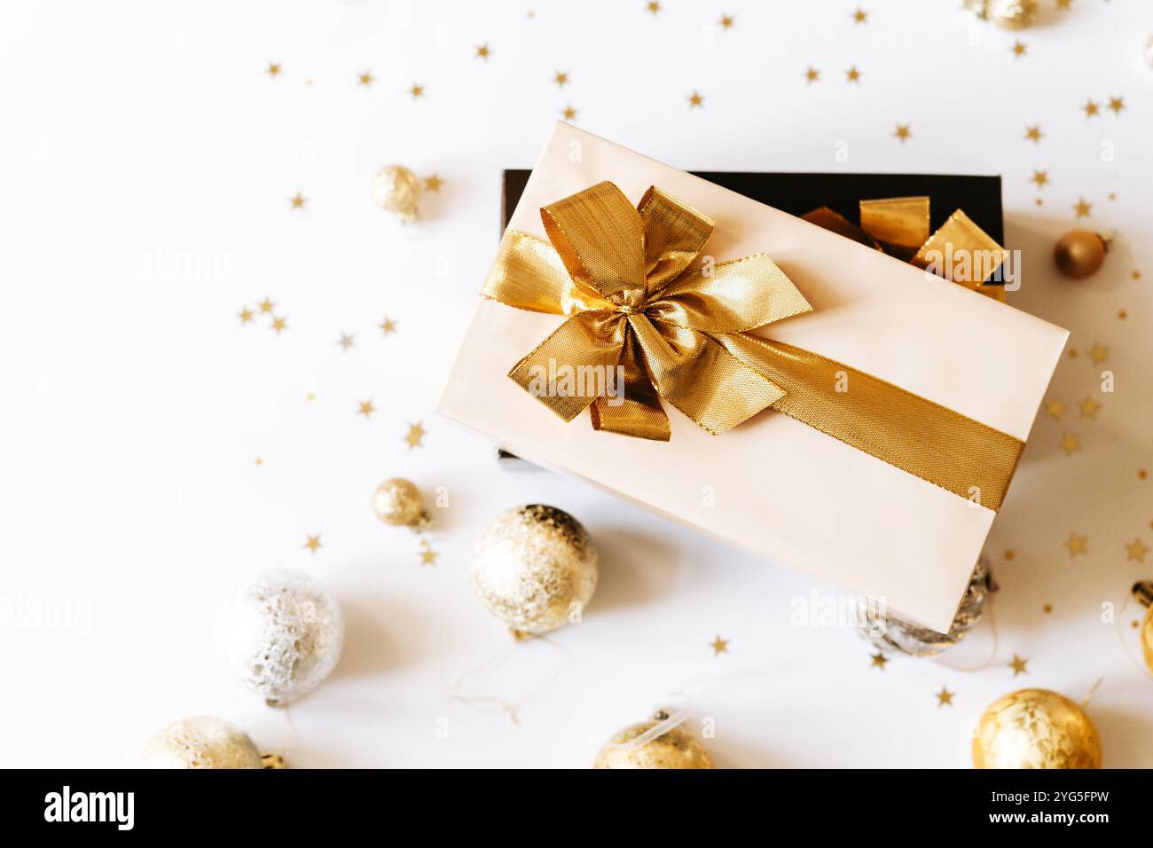 Two Christmas gift boxes, adorned with vibrant golden ribbons on white background. Flat lay. Copy space Stock Photo