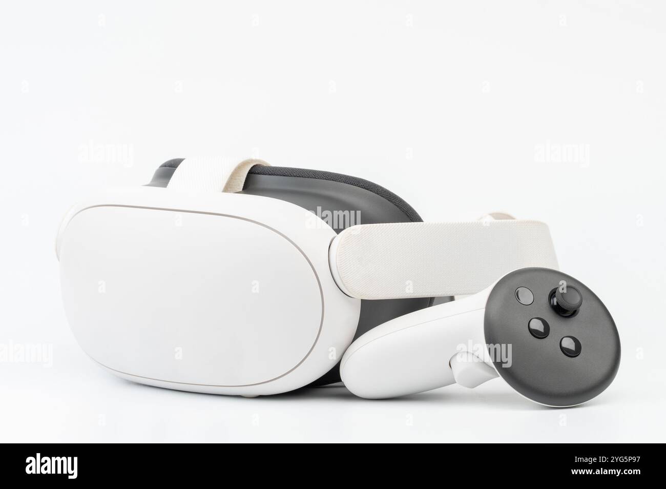 Virtual reality headset paired with controller rests on smooth surface, showcasing sleek, modern technology. Stock Photo