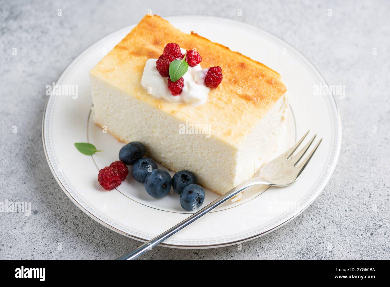 Cottage cheese casserole with fresh berries on a white plate. Healthy baked cheesecake, zapekanka Stock Photo