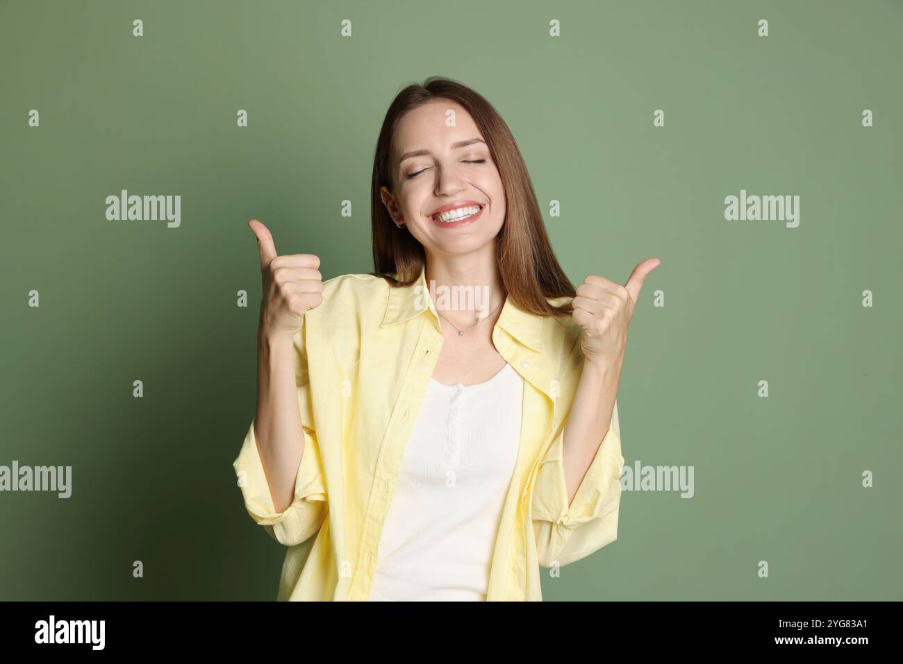 Happy winner showing thumbs up on green background Stock Photo - Alamy