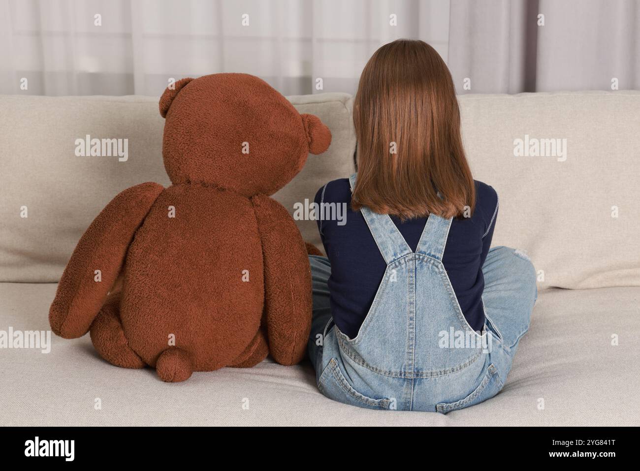 Autism concept. Lonely little girl with teddy bear on sofa at home ...