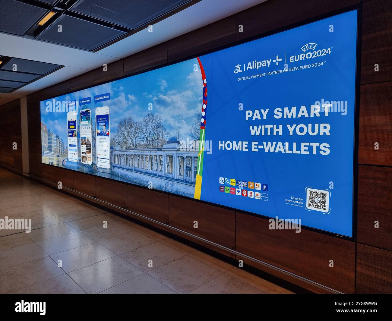 Commercial banner / display in Berlin Brandenburg Airport for Alipay home e-wallets during Euro2024 - Smartphone Captured Stock Image