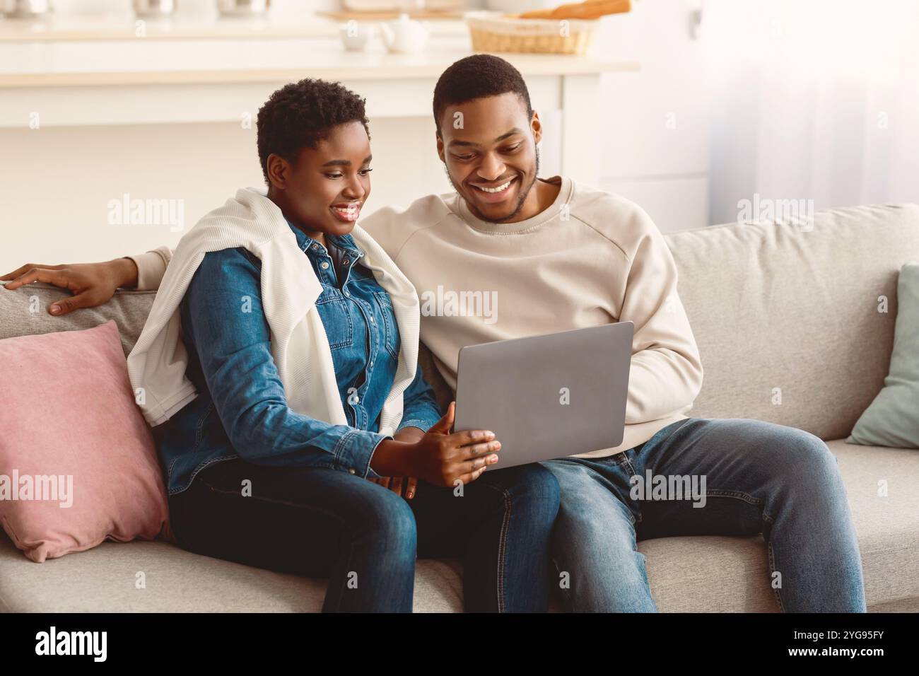 African american couple sitting on couch, using laptop Stock Photo - Alamy