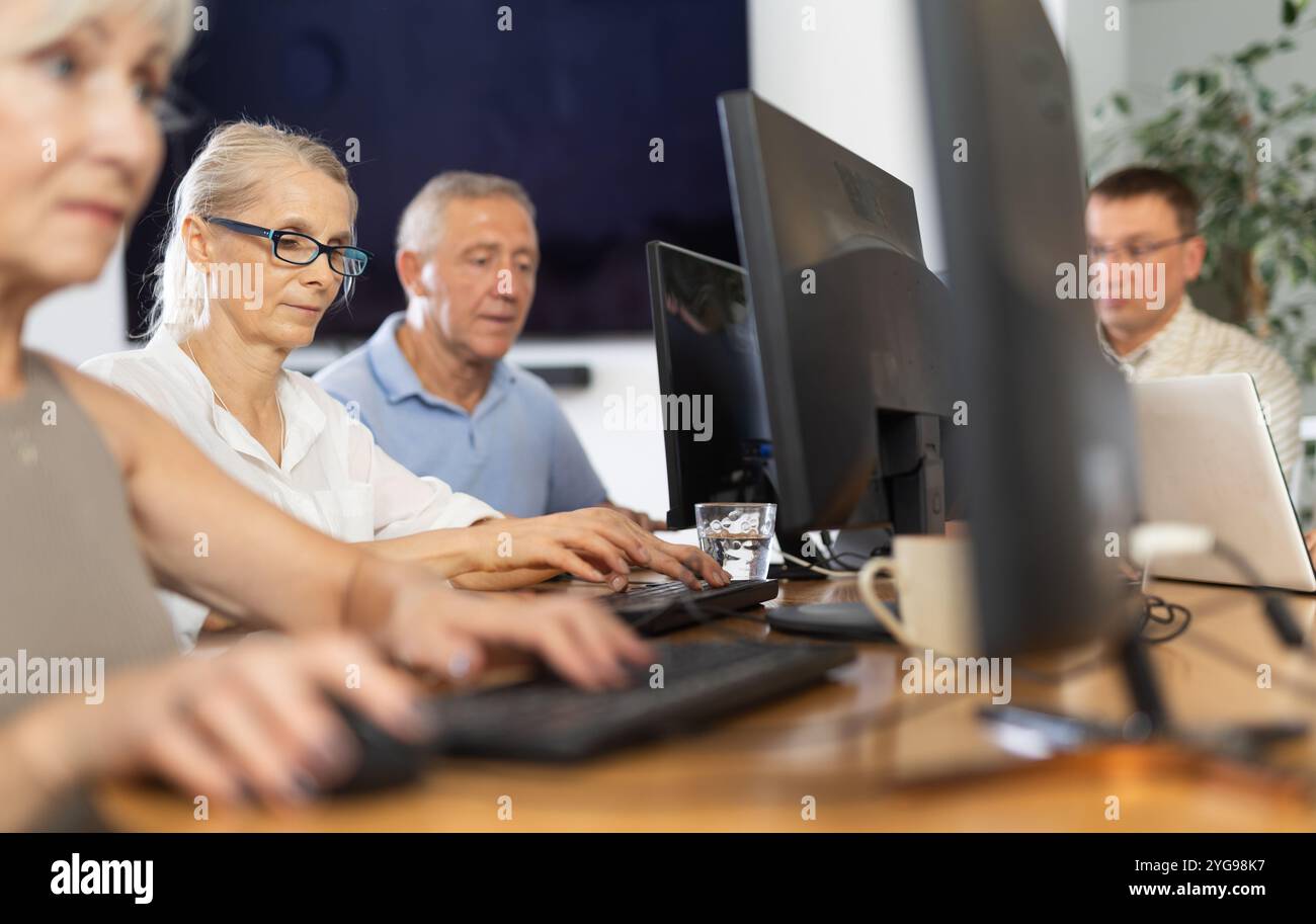 Old woman learning computer programs in training room Stock Photo