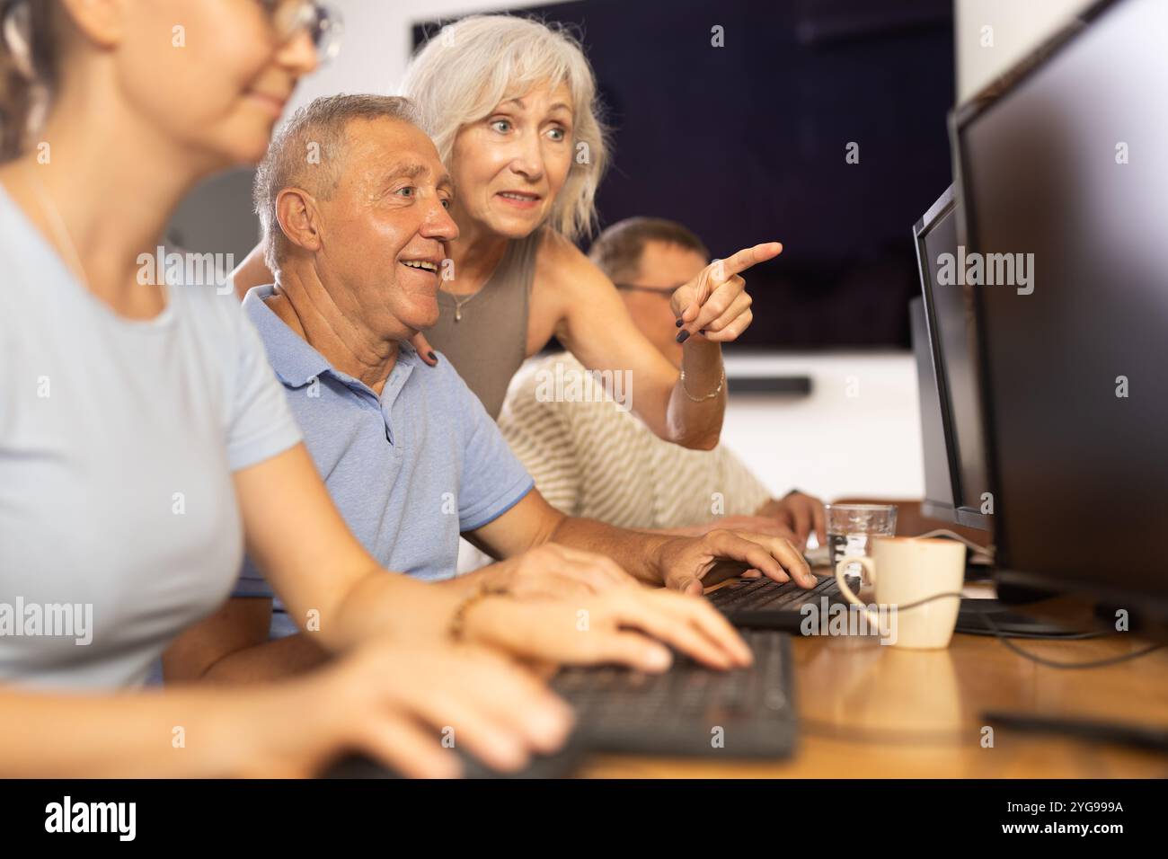 Older female mentor explaining something to elderly man at computer class Stock Photo