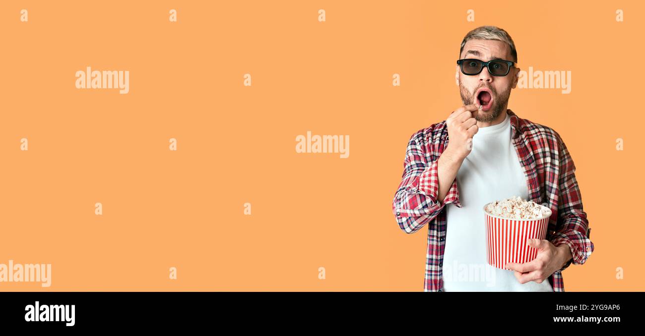 Surprised man in 3D glasses eating popcorn Stock Photo