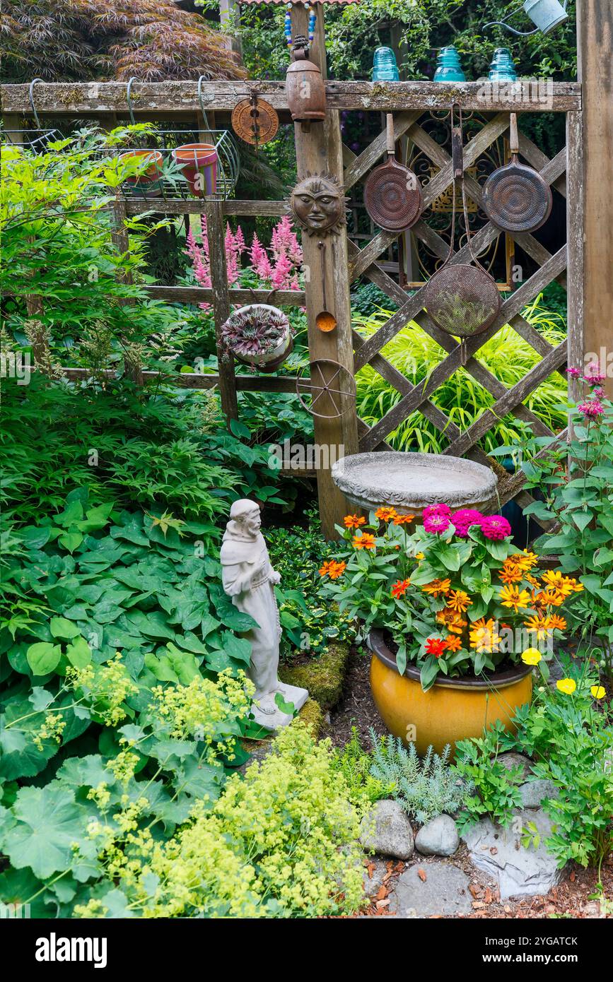 USA, Washington State, Sammamish. Garden with fence and flower pots. Bird bath and garden art and pot with zinnias Stock Photo