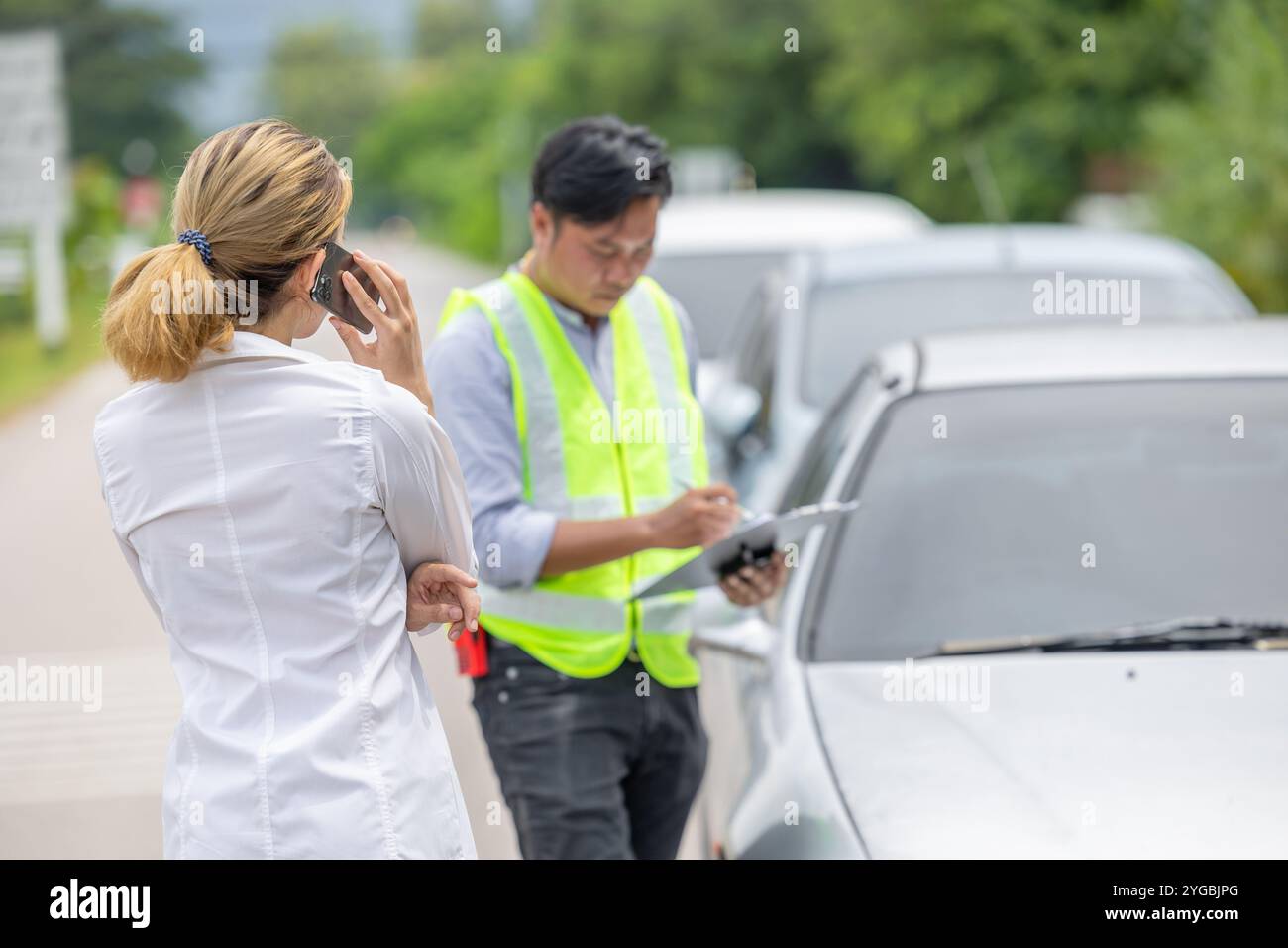 Women car problem crash talking phone call for help insurance man officer agent roadside damage assessment report. Stock Photo