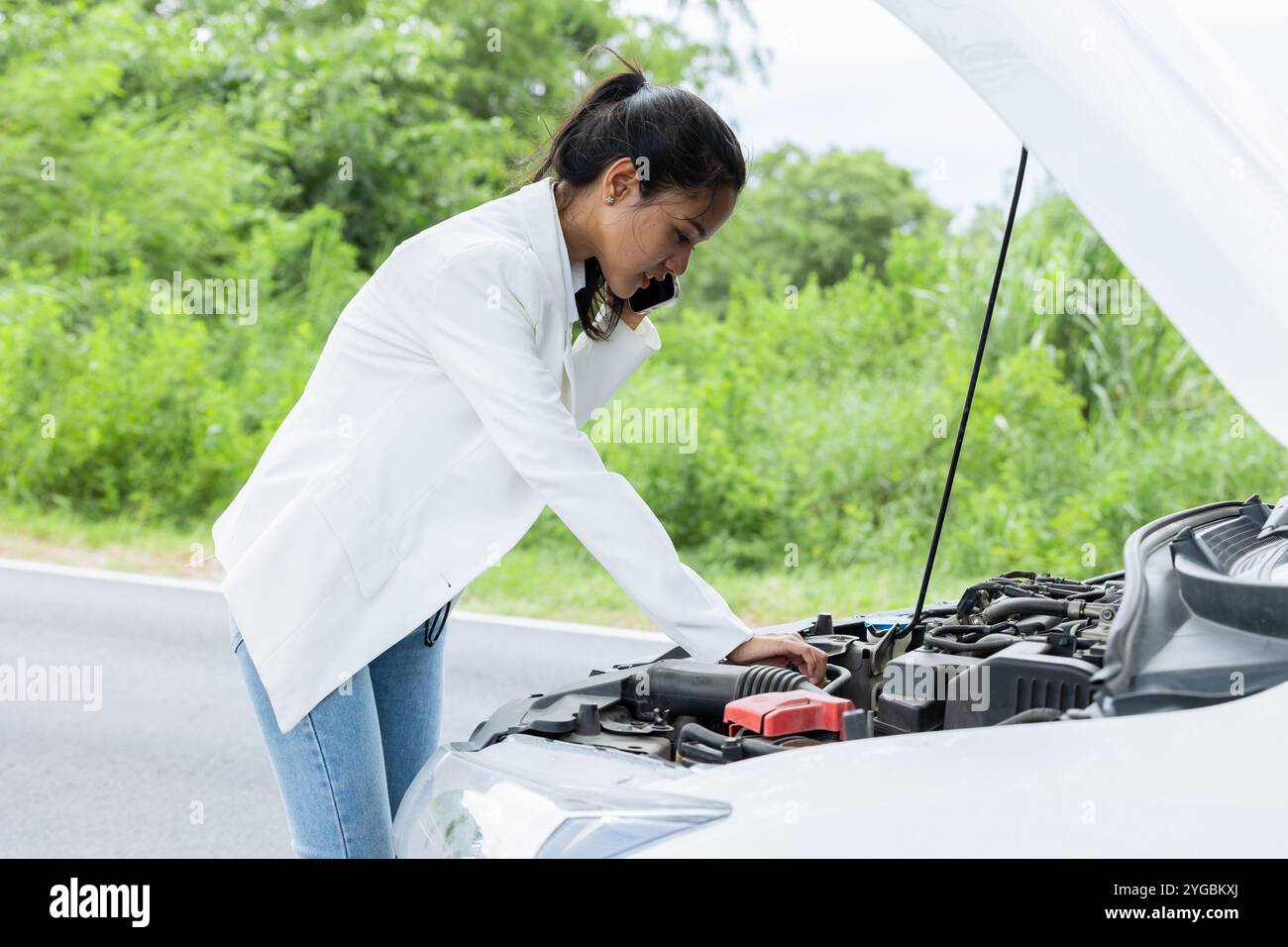 Young woman calling help and insurance auto service with a problem broken car on the road, angry upset worry expression. Stock Photo