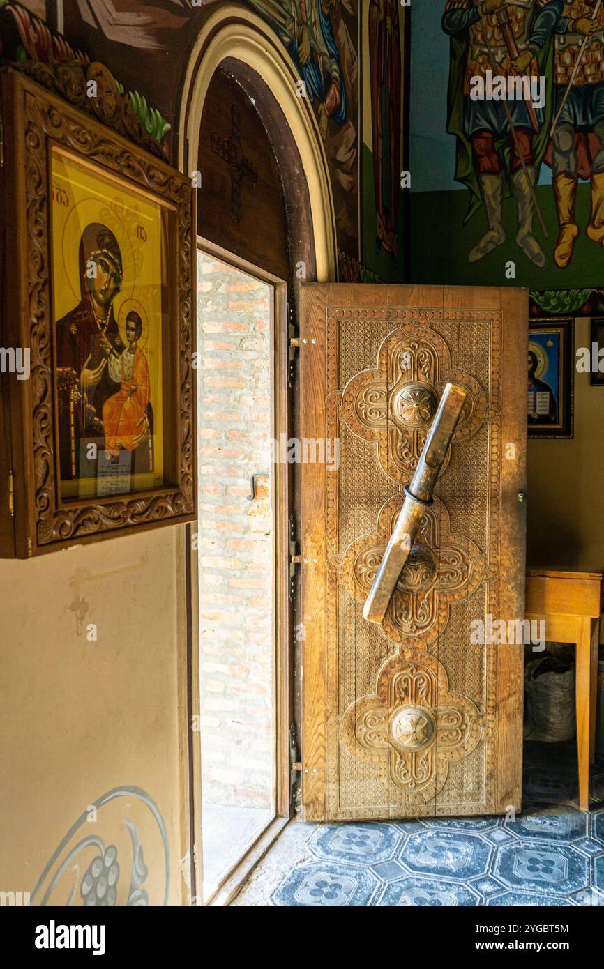 A carved wooden door in a church with a huge handle. Icons and wall ...
