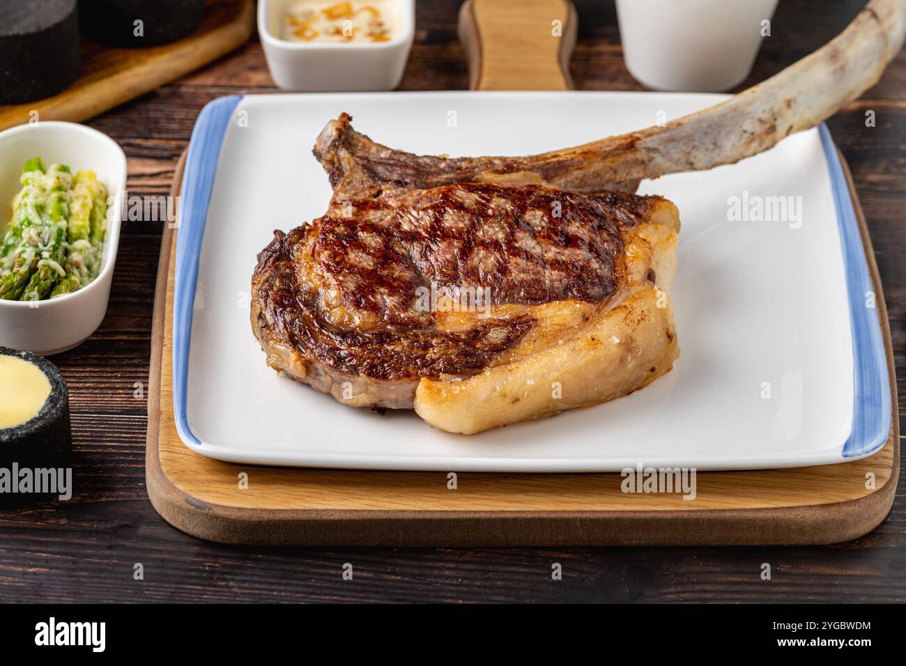 Grilled veal chop on white porcelain plate on wooden table Stock Photo