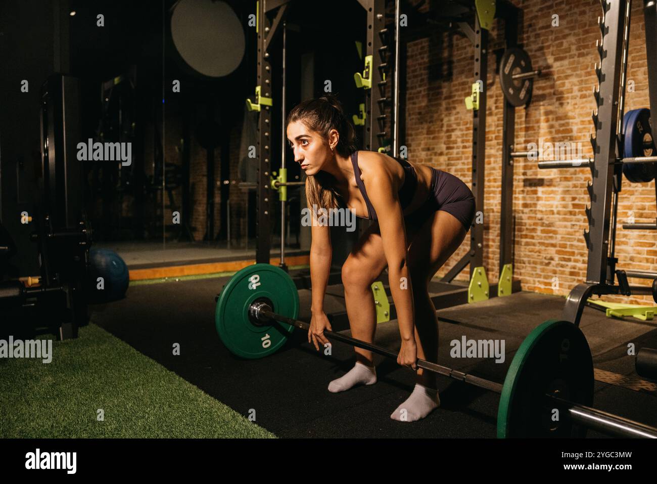 A focused and determined woman exercises in a gym, lifting weights as ...