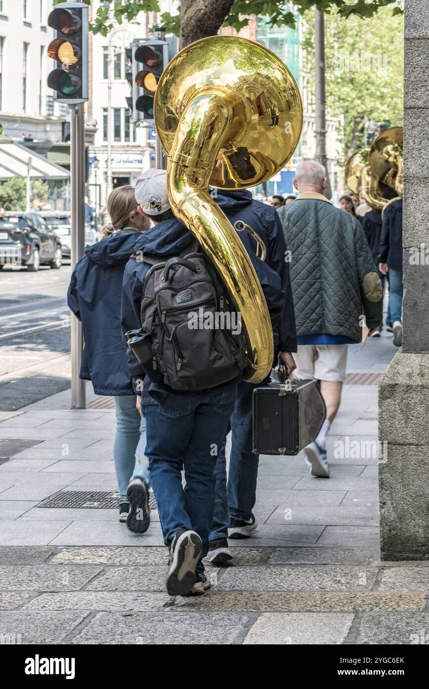 A man with a sousaphone on his back walking down in Dublin, Ireland. Stock Photo