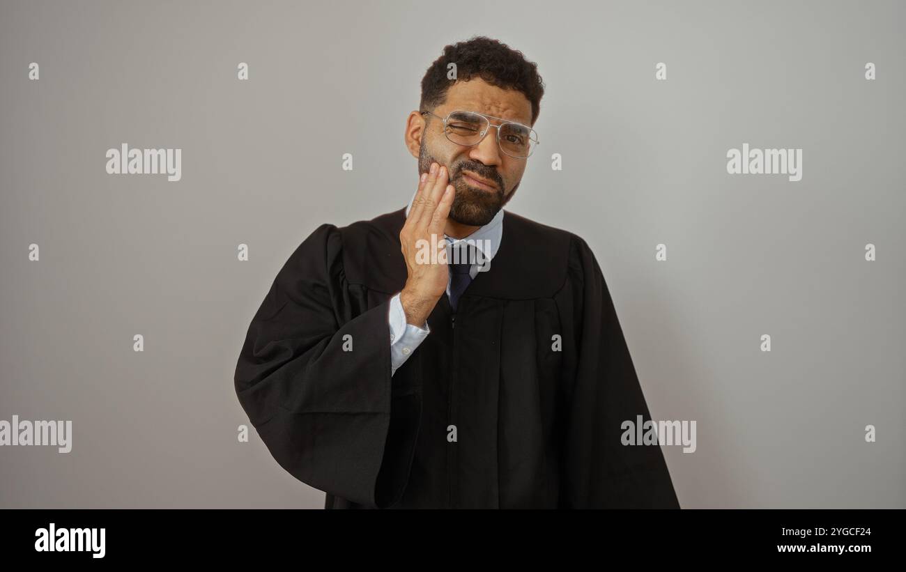 Young man in graduation gown over white background with unhappy ...