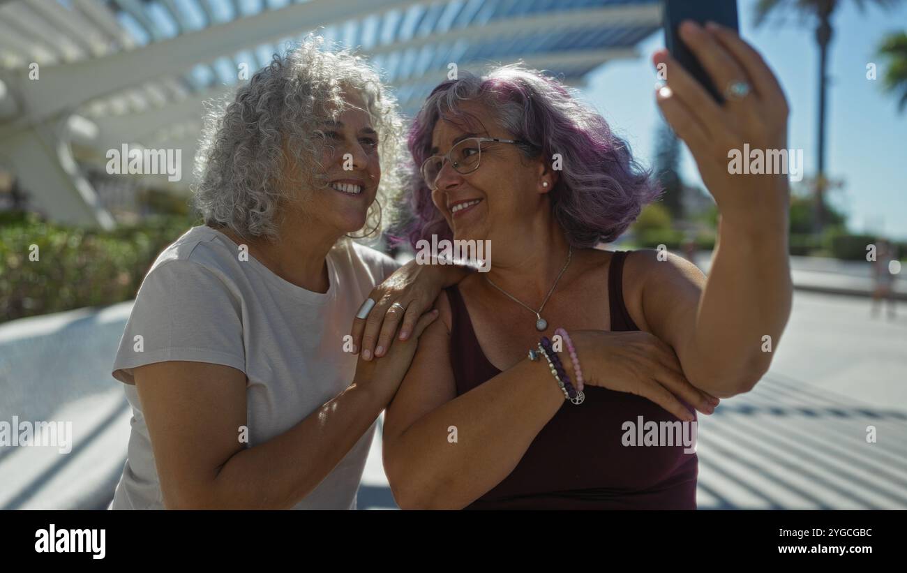 Two elderly women taking a selfie together in an outdoor setting, their ...