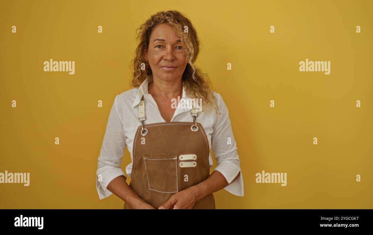 Mature hispanic woman with curly hair wearing a brown apron standing ...
