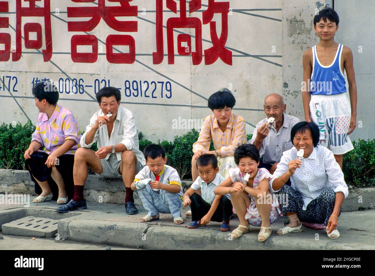 China, Shanghai, family is eating ice cream on the pavement. Stock Photo