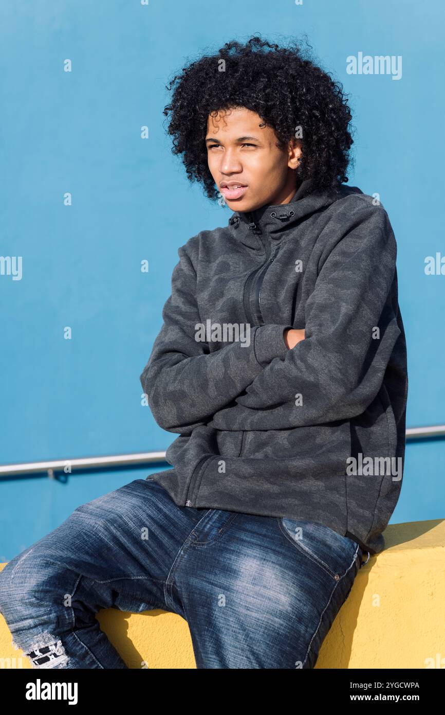 teenager with curly hair sitting with arms crossed Stock Photo - Alamy