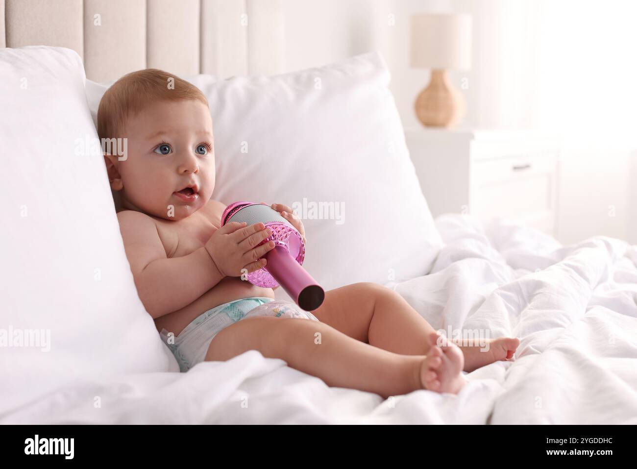 Cute little baby with microphone on bed at home, space for text Stock ...