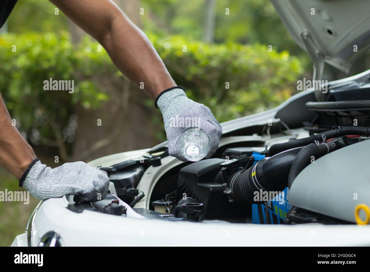 mechanic is checking car and adding water to radiator to increase the ...