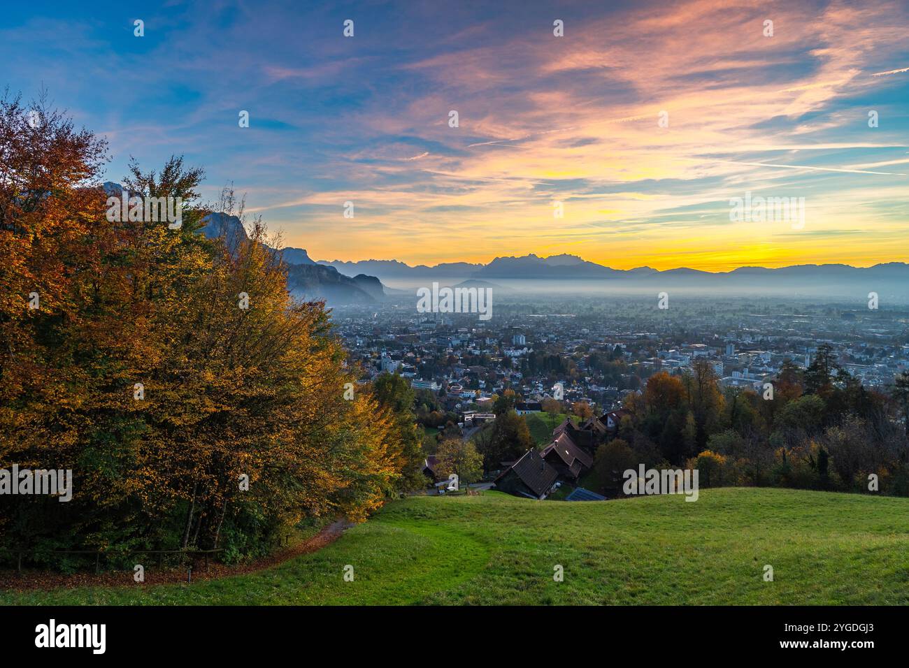 Panorama Sunset in the Rhine Valley, with afterglow, blue sky over the city of Dornbirn, meadow and fields. autumn colored trees. beautiful recreation Stock Photo