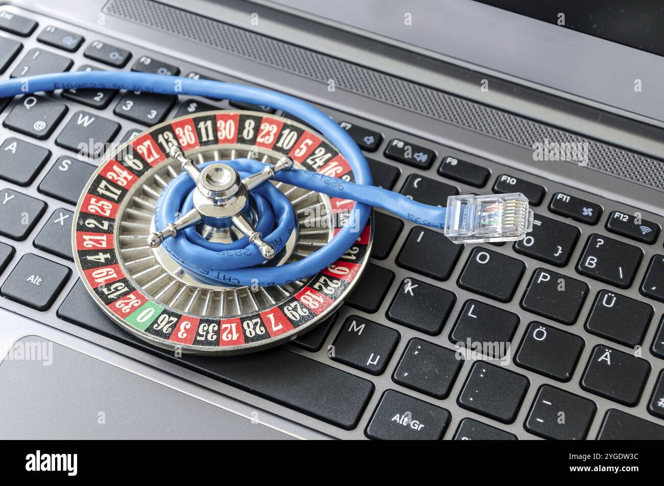 Roulette wheel and internet cable lying on computer keyboard symbolizing data encryption Stock Photo