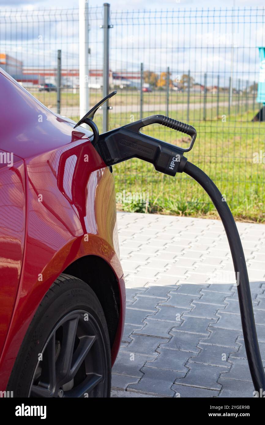 Red full electric Tesla Model 3 at the charge station in Lithuania Stock Photo