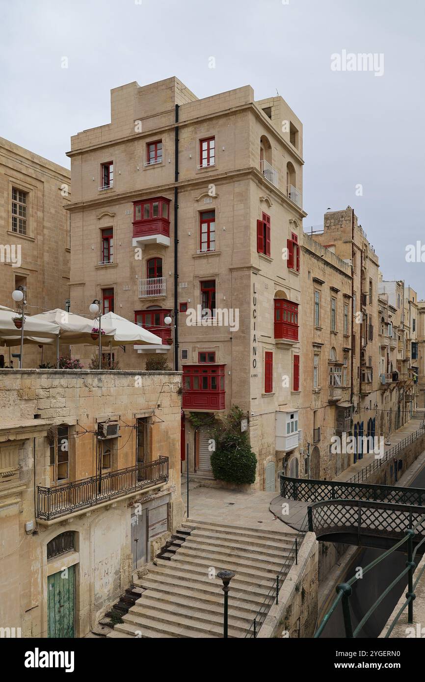 Valletta. Malta. Haus. Erker. Kalkstein. bay window. rote Fenster. red bay window. rote Erker. Brücke . bridge. rote Fensterläden. shutter. red. Stock Photo