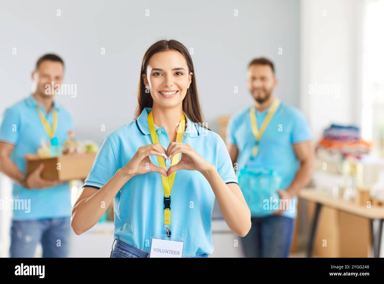 Young happy woman volunteer making heart gesture volunteering in charitable foundation Stock Photo
