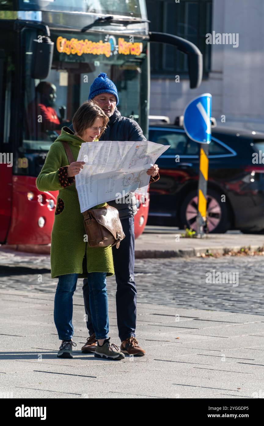 A couple of tourists stop to look at their city map of Oslo in Norway.  Oslo, the capital city of Norway, sits on the country’s southern coast at the Stock Photo