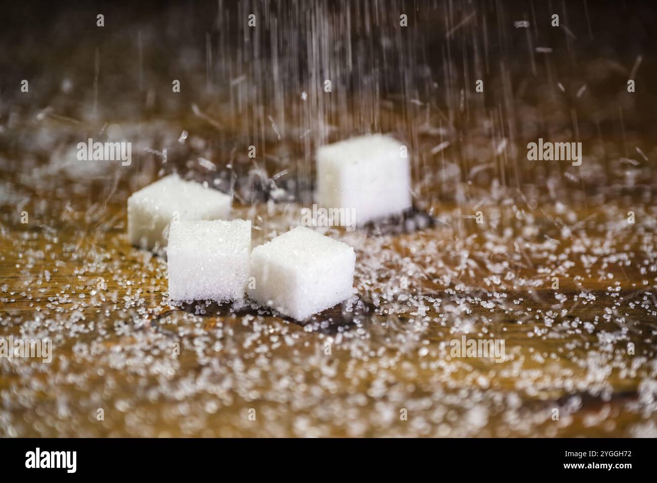 Sugar cubes on a pile of white refined granulated sugar, close up. Weight gain and risk of heart disease concepts. Stock Photo