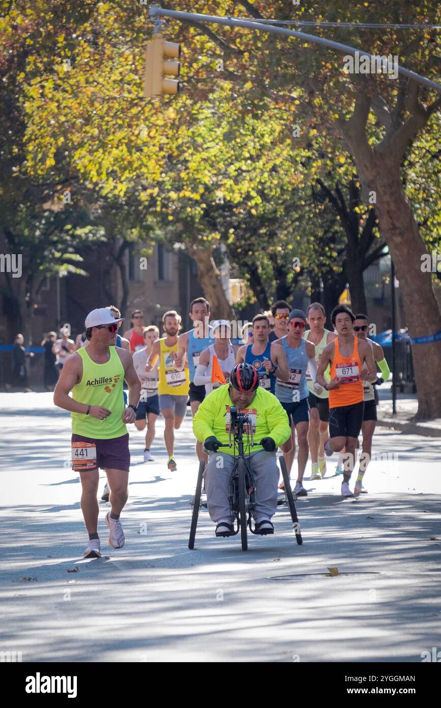 In the 2024 NY Marathon, an elite group of runners behind a Wheelchair