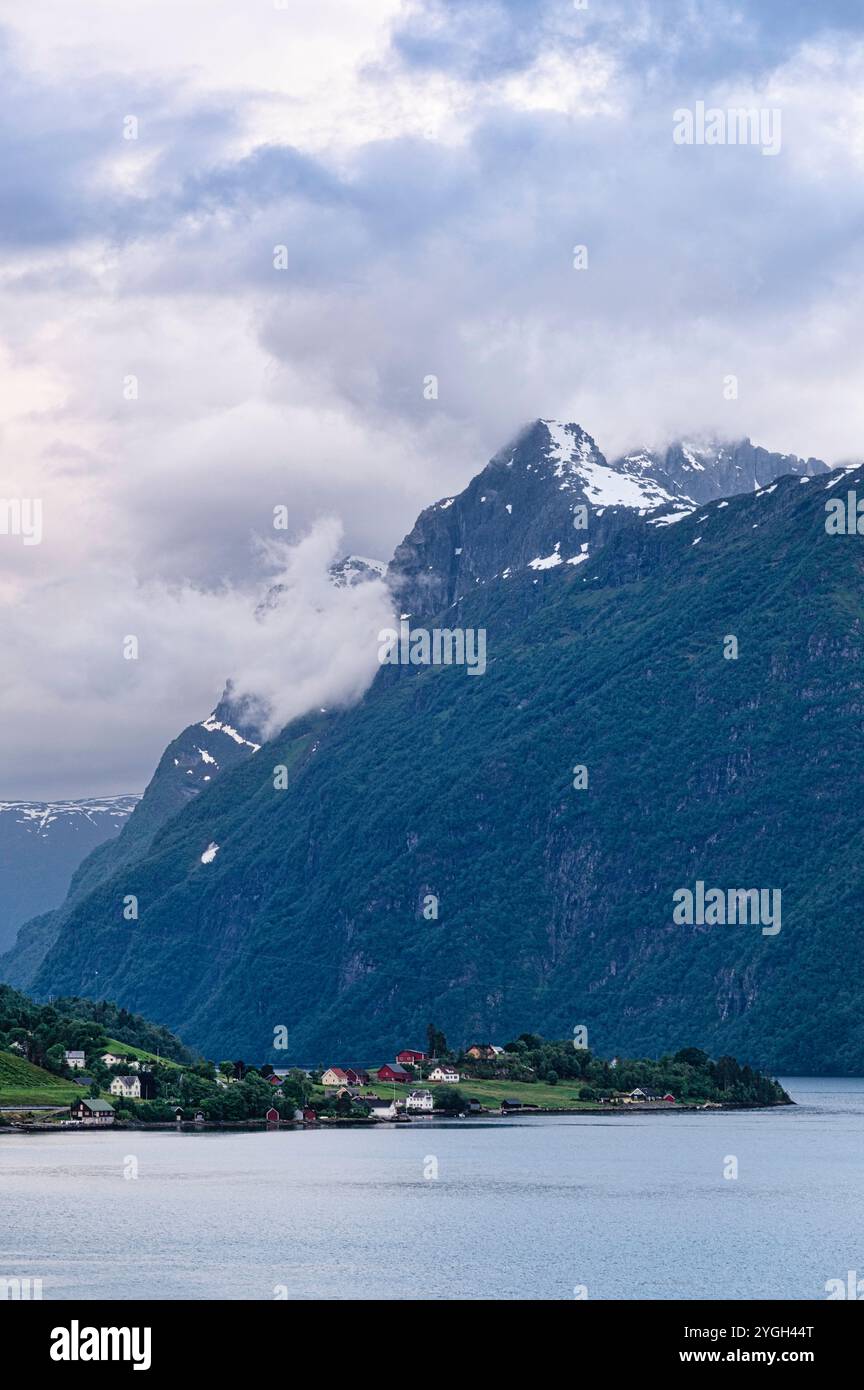 Norwegian village landscape with fjord, mountains, clouds and colorful ...