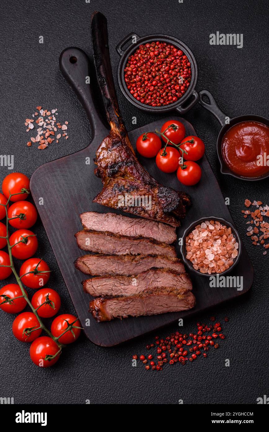Grilled wagyu beef tomahawk steak with salt, spices and herbs on a dark ...