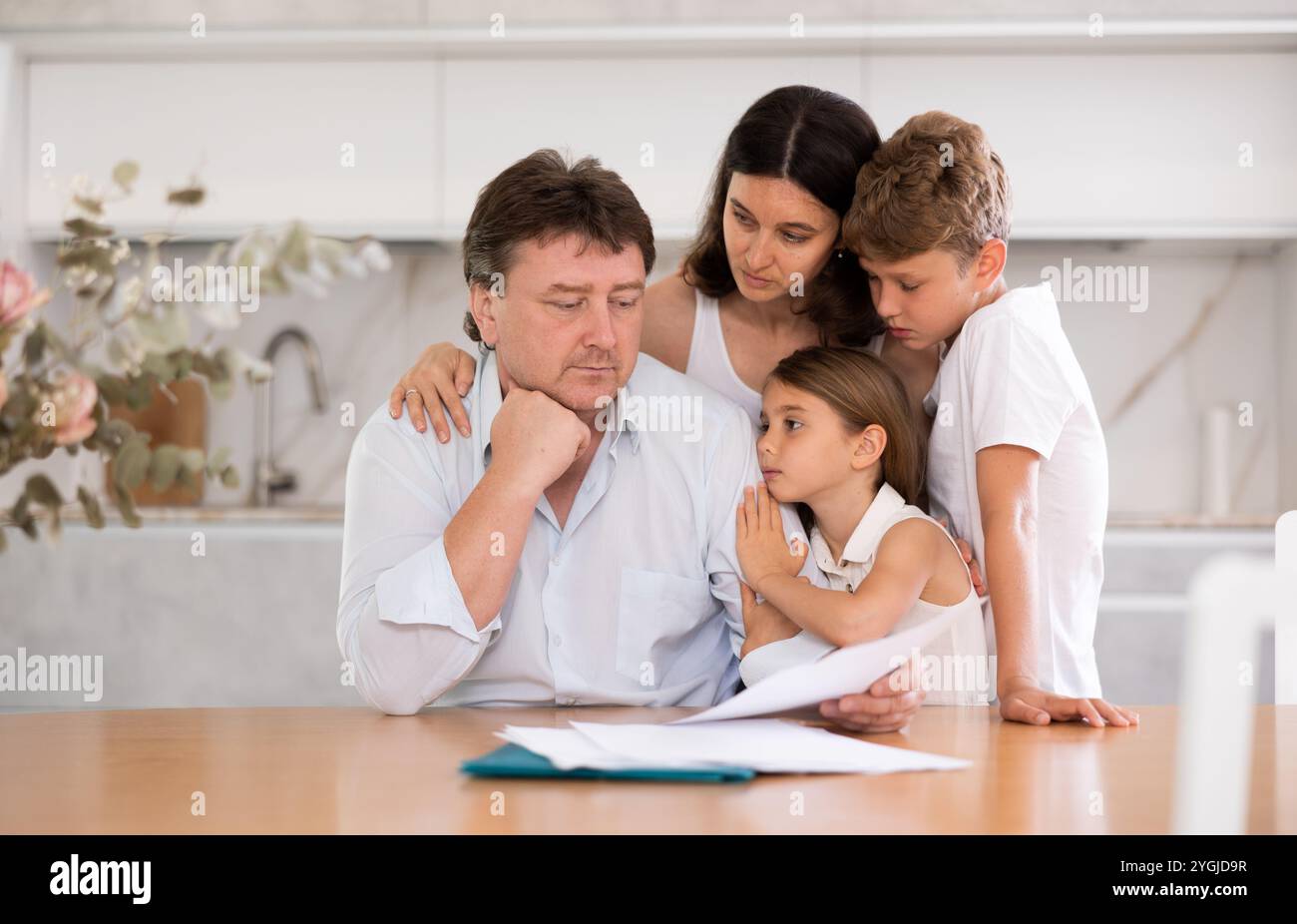Wistful father looking through papers with family Stock Photo - Alamy
