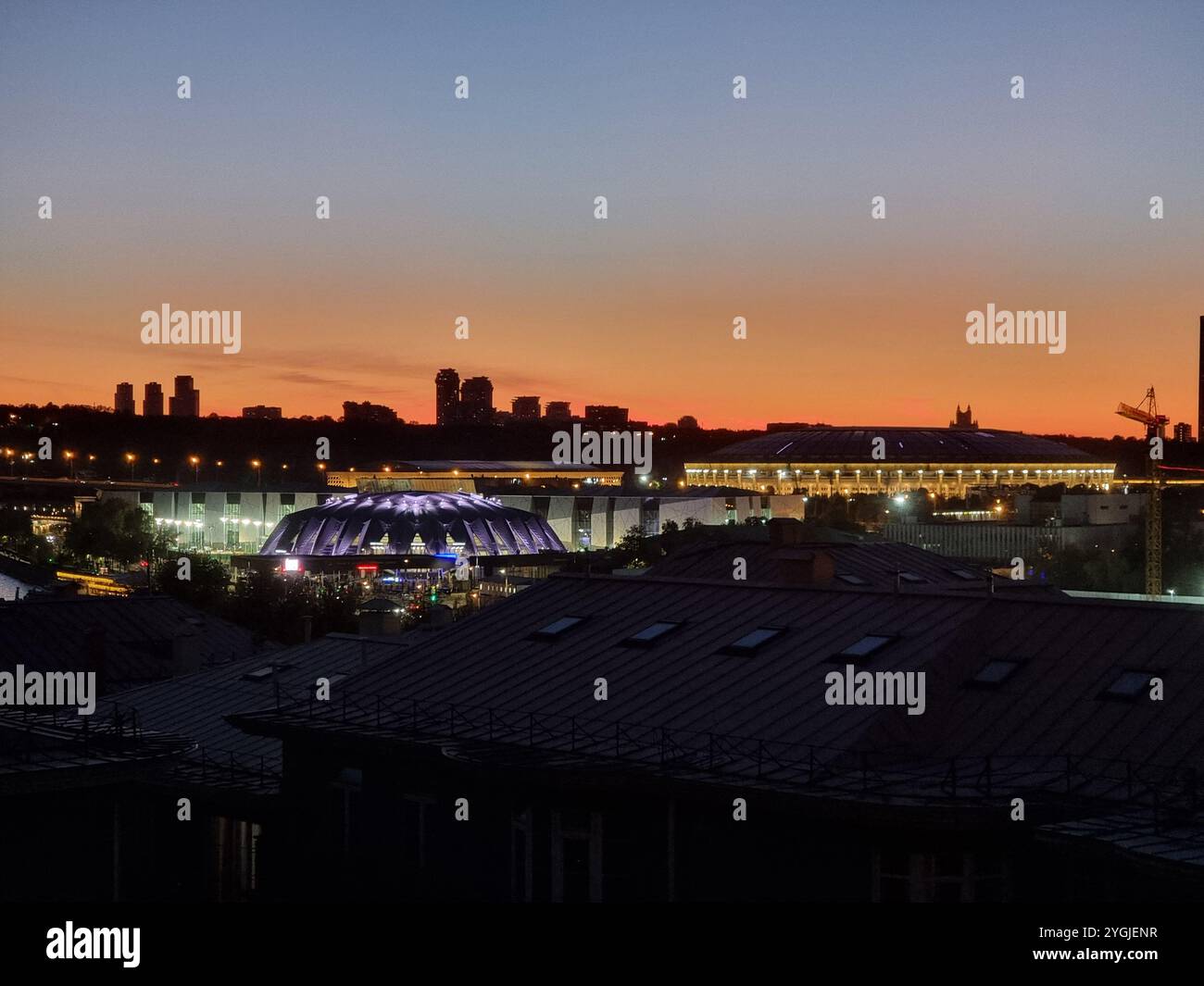 Evening view of Moscow skyline with blue lit Luzhniki stadium / Grand Sports Arena of the Luzhniki Olympic Complex against a coloured, orange red sky - Smartphone Captured Stock Image