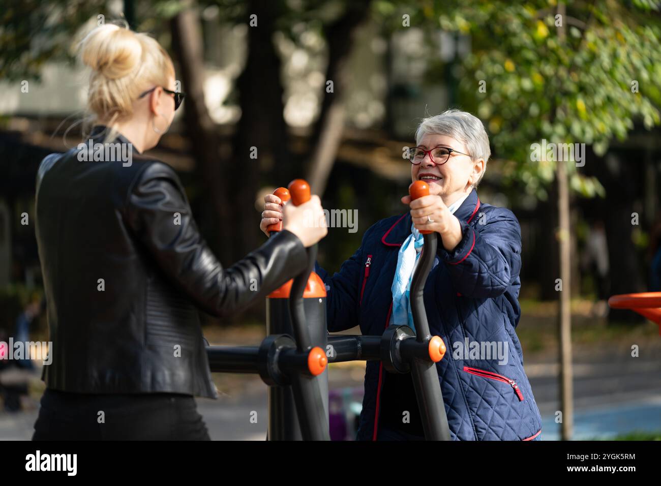 A senior woman and her daughter, both dressed casually, work out ...