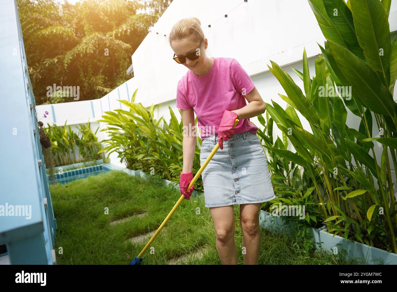 Woman Racking Lawn A woman raking the lawn at the backyard of her house Stock Photo - Alamy